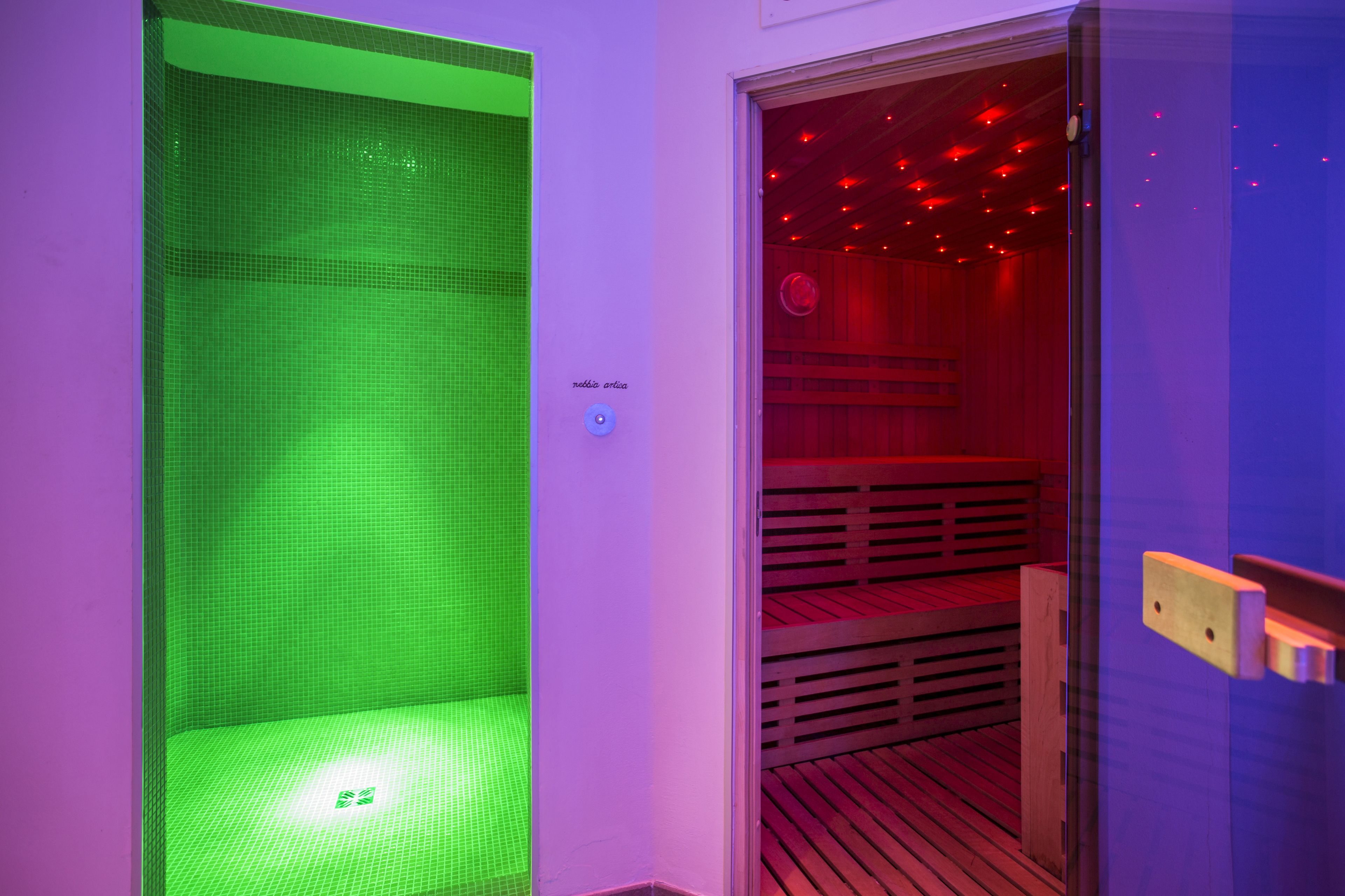 Una sala de sauna con suelo de baldosas verdes y un banco de madera.
