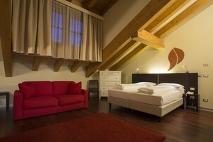 A bedroom with a bed, a red sofa, a dresser, and a wooden ceiling.