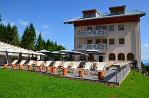 Un hotel con terraza, sillones de sol y zona de piscina.