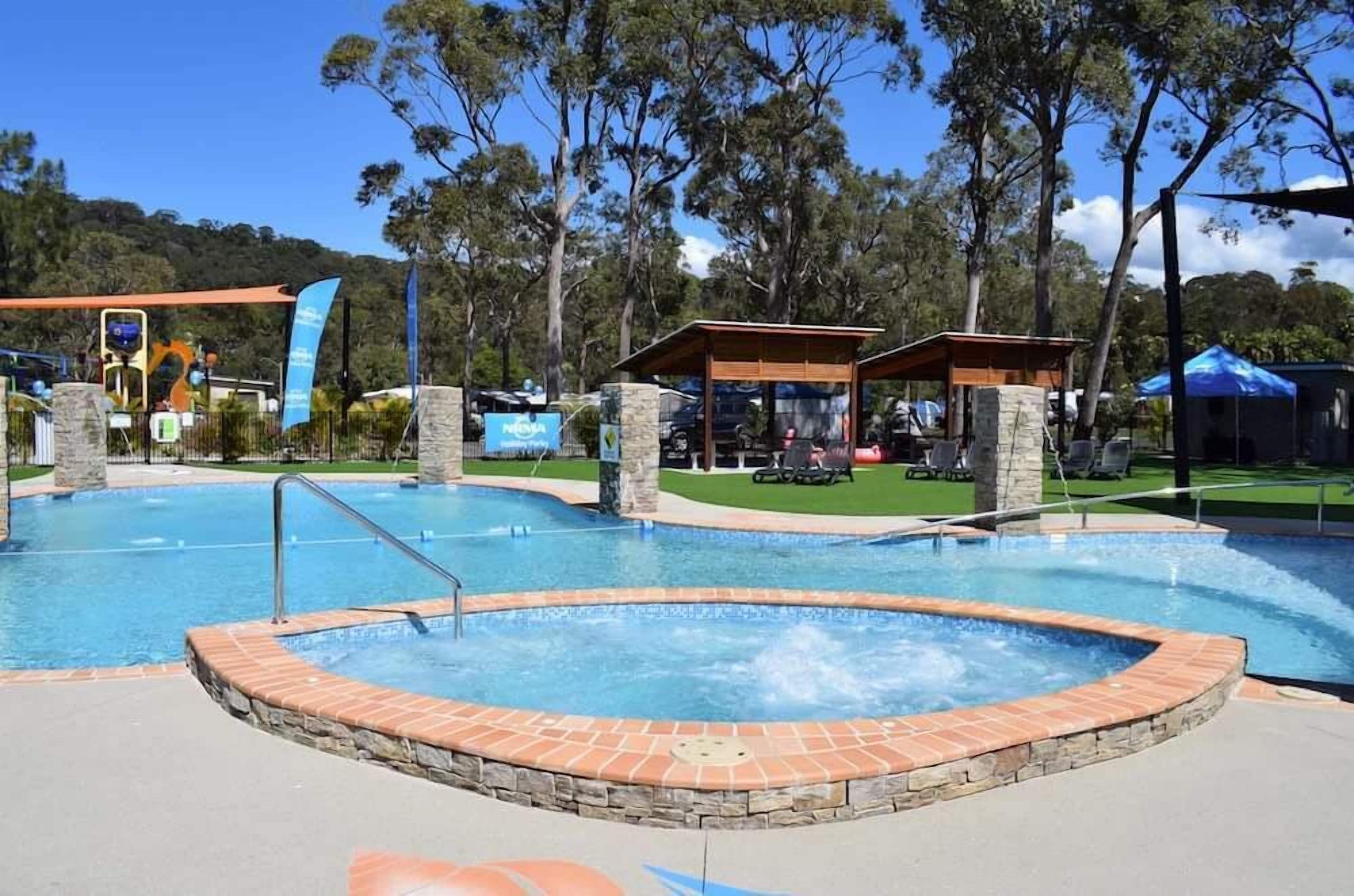 Un espace piscine comprenant un jacuzzi, des chaises longues et un coin salon abrité.