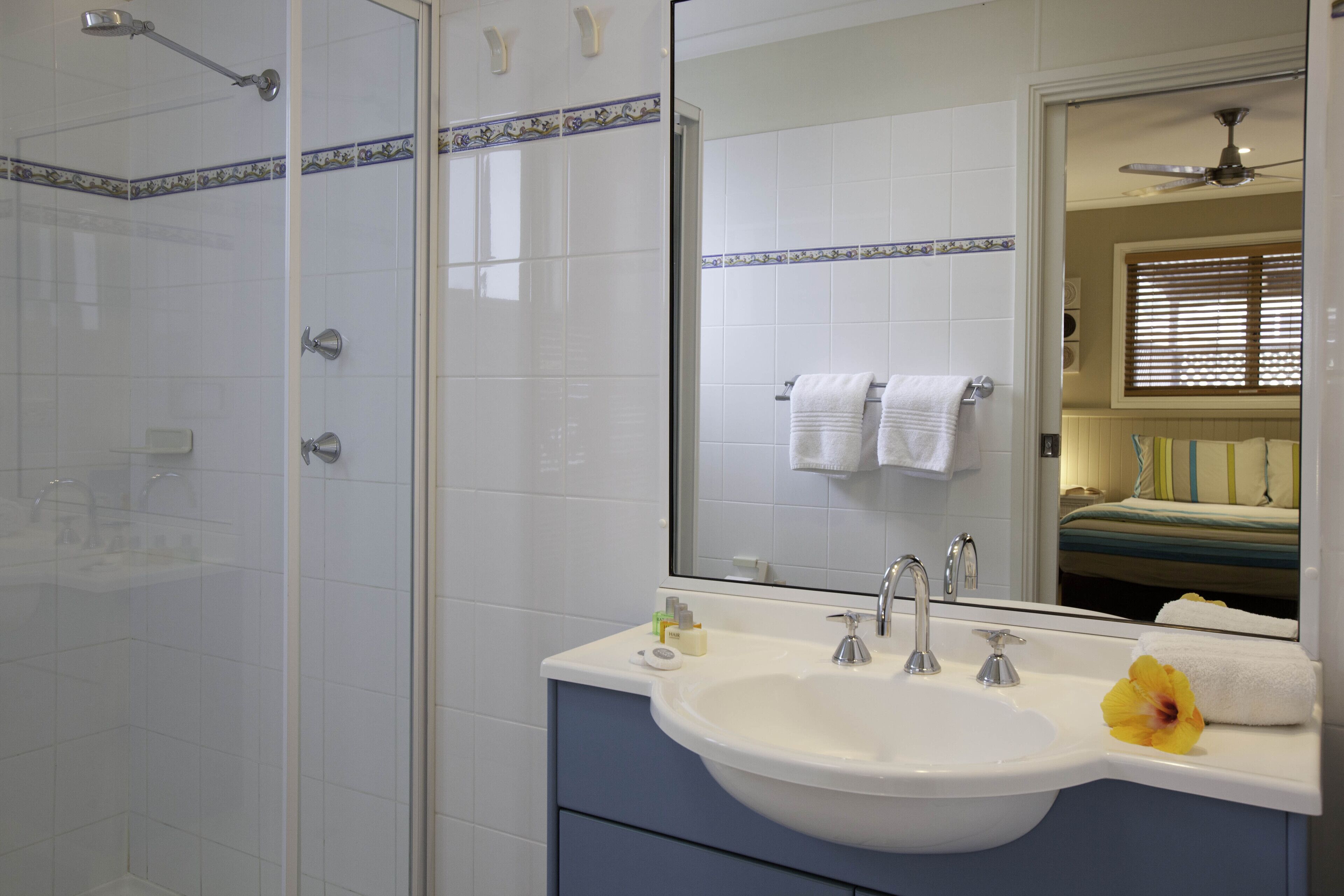 Une salle de bain avec un lavabo blanc, un miroir et une douche.