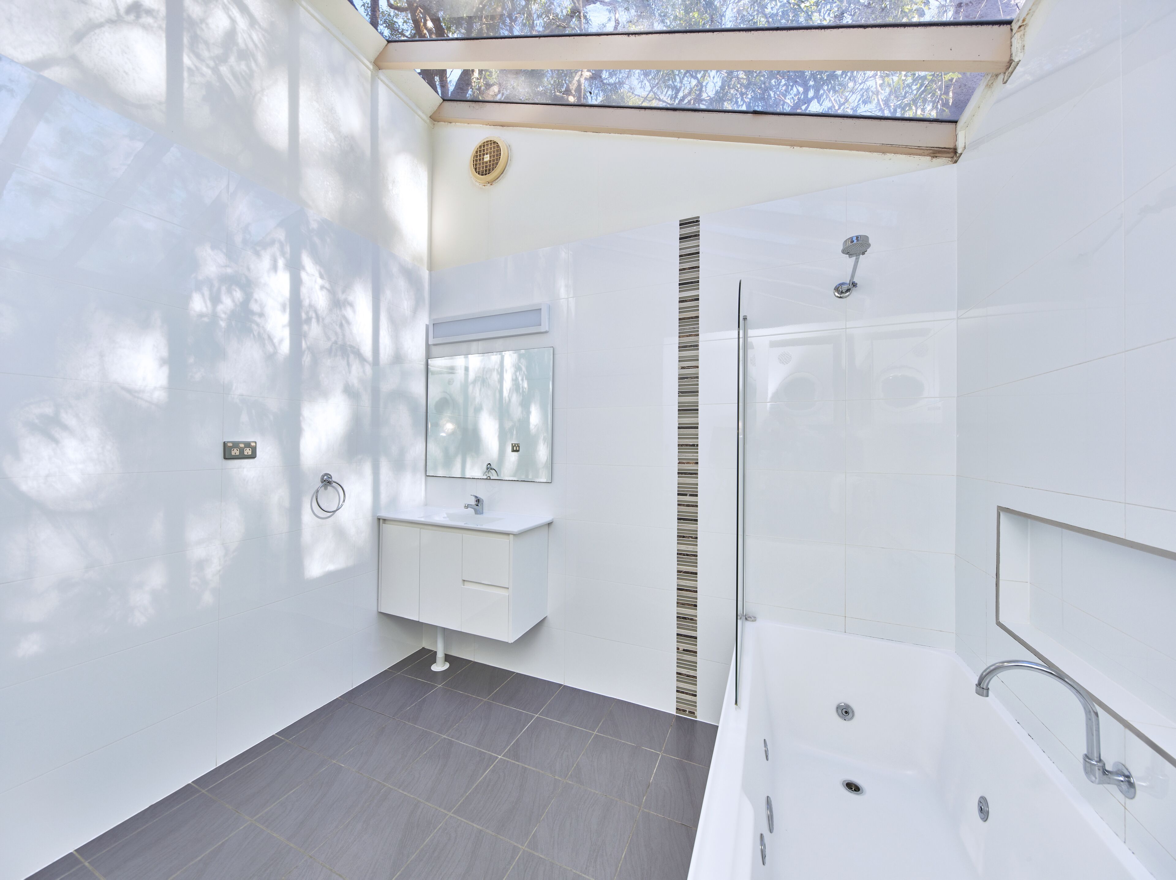 A modern bathroom with a large bathtub, a separate shower area, and a vanity with a mirror.
