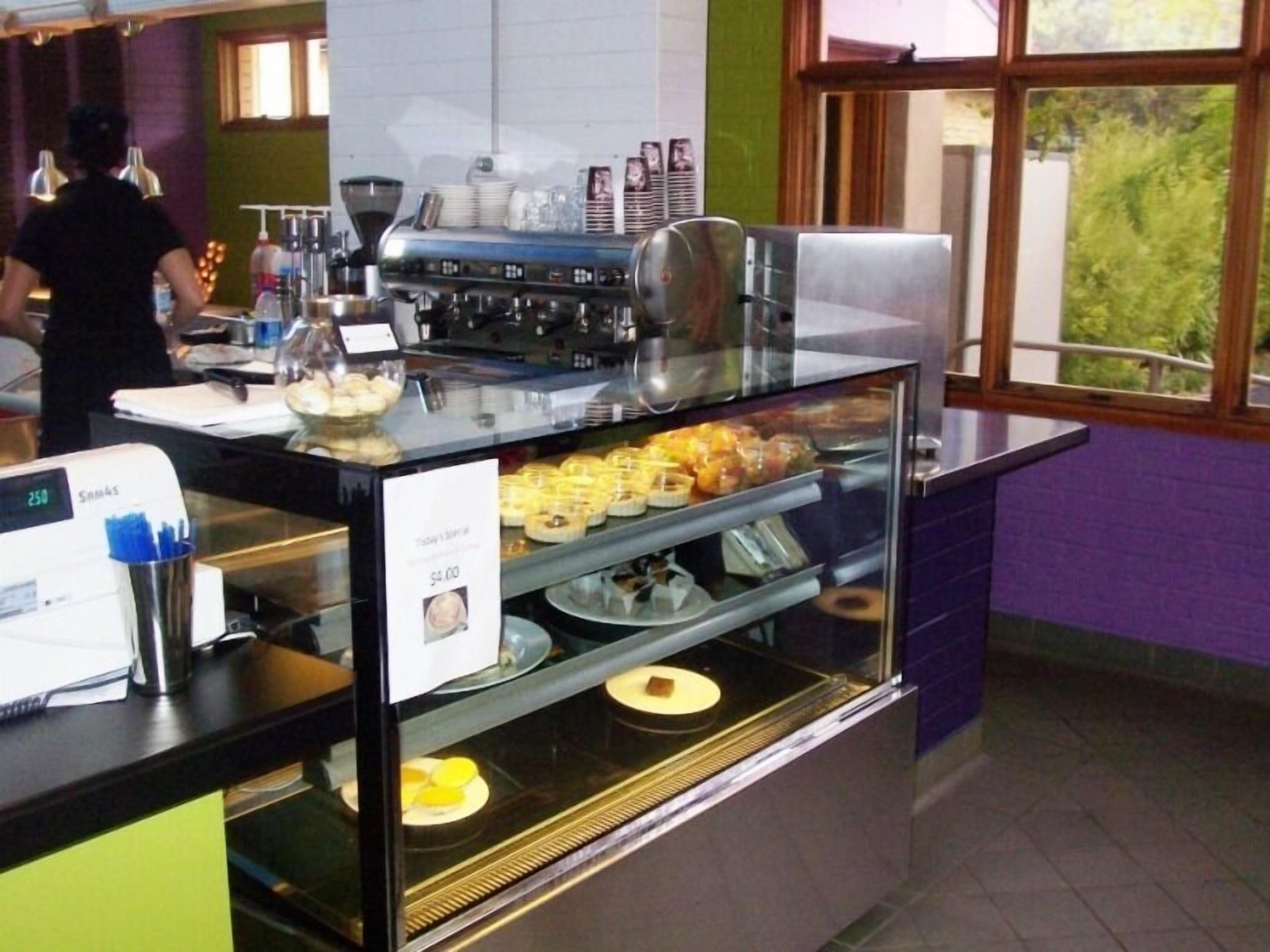 A bakery display case with pastries and a coffee machine.