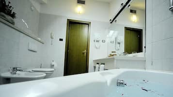 Un baño moderno con bañera, dos lavamanos y un inodoro. Hay dos puertas, una de ellas abierta.