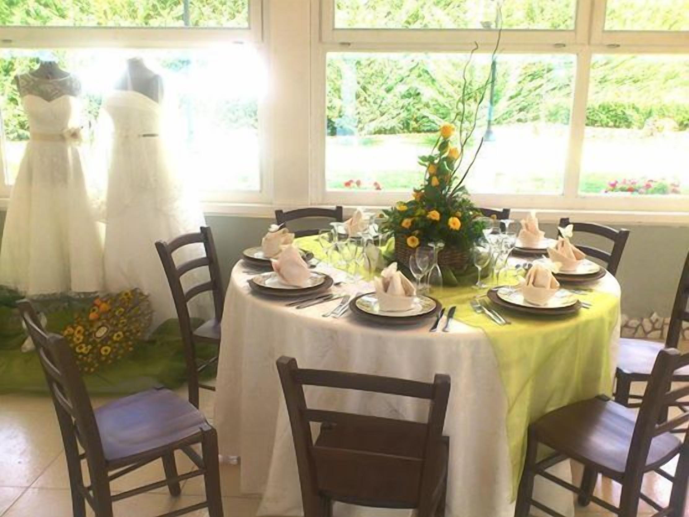 A dining table set for six with a yellow tablecloth, surrounded by wooden chairs.