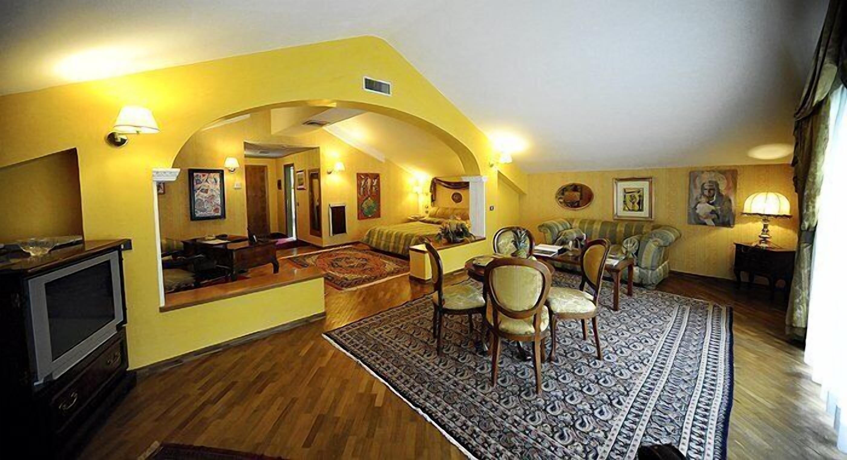 A living room with a sofa, chairs, a TV, and a patterned rug.