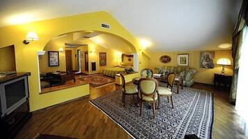A living room with a sofa, chairs, a TV, and a patterned rug.