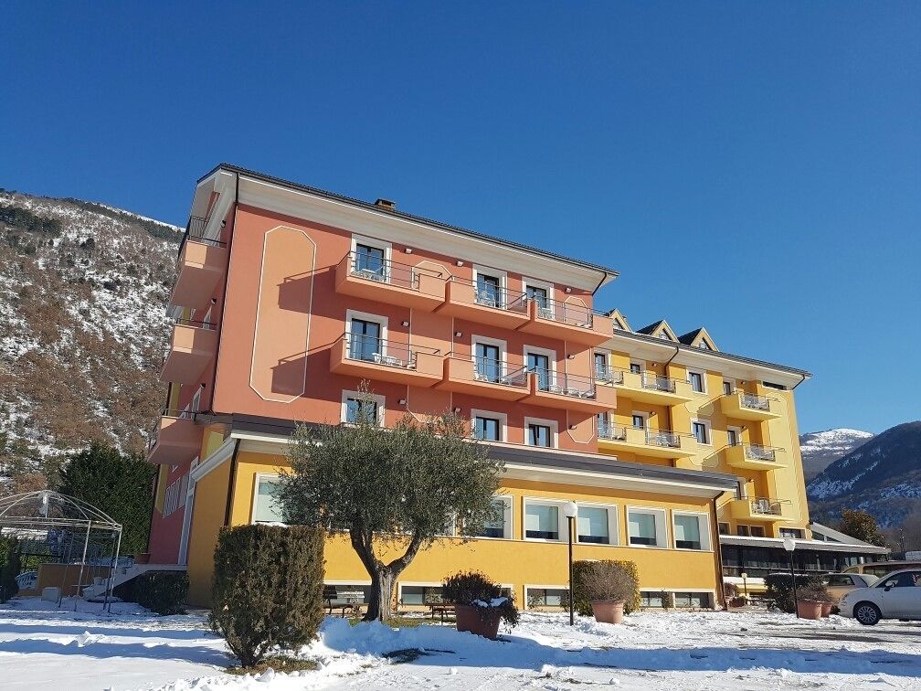 A multi-story hotel with balconies, a parking area, and snow-covered surroundings.