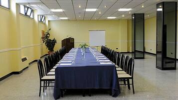 Une salle de conférence équipée d’une longue table, de chaises, d’un pupitre et d’un tableau blanc.