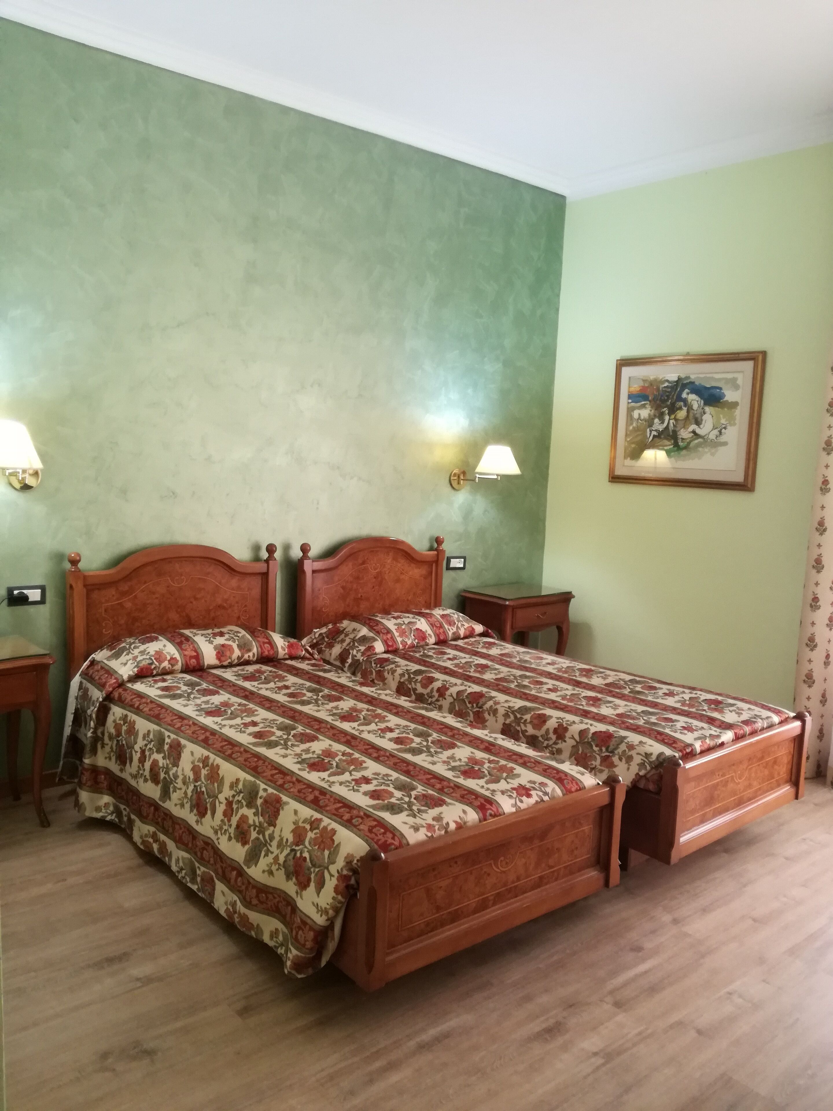 A bedroom with a wooden bed, green walls, and a framed picture on the wall.