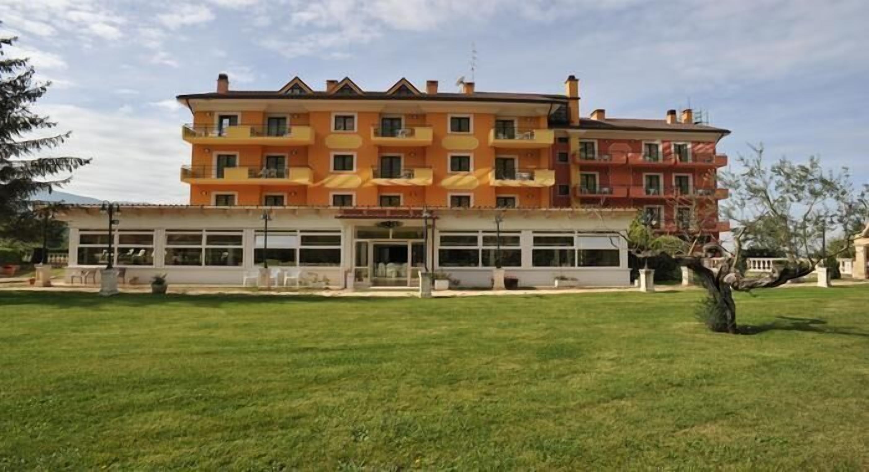 A multi-story hotel with a central courtyard, balconies, and a flat roof.
