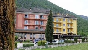 A multi-story hotel with balconies and a mountain backdrop.