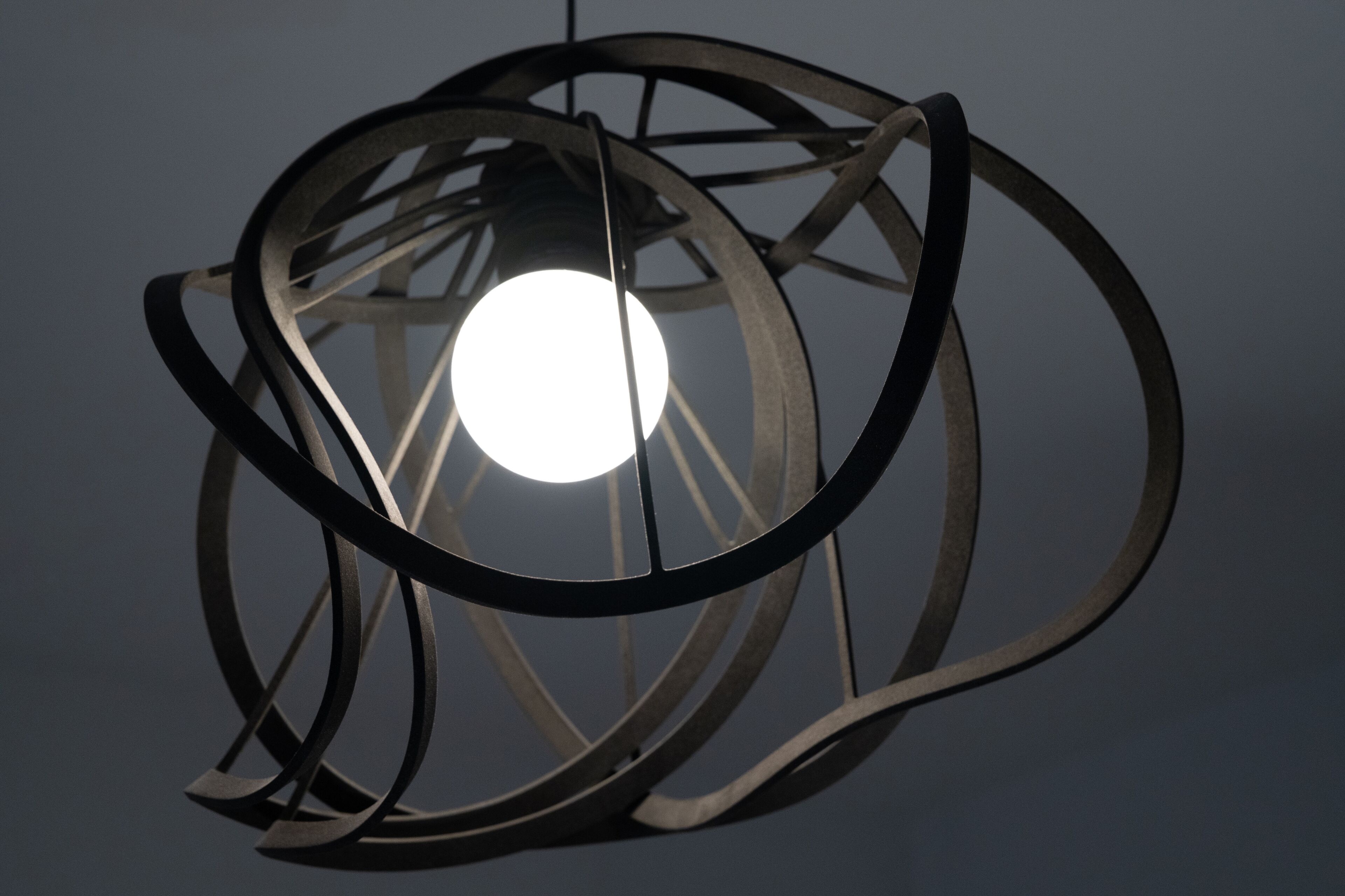 En sfärisk metallarmatur med en lampa i mitten.