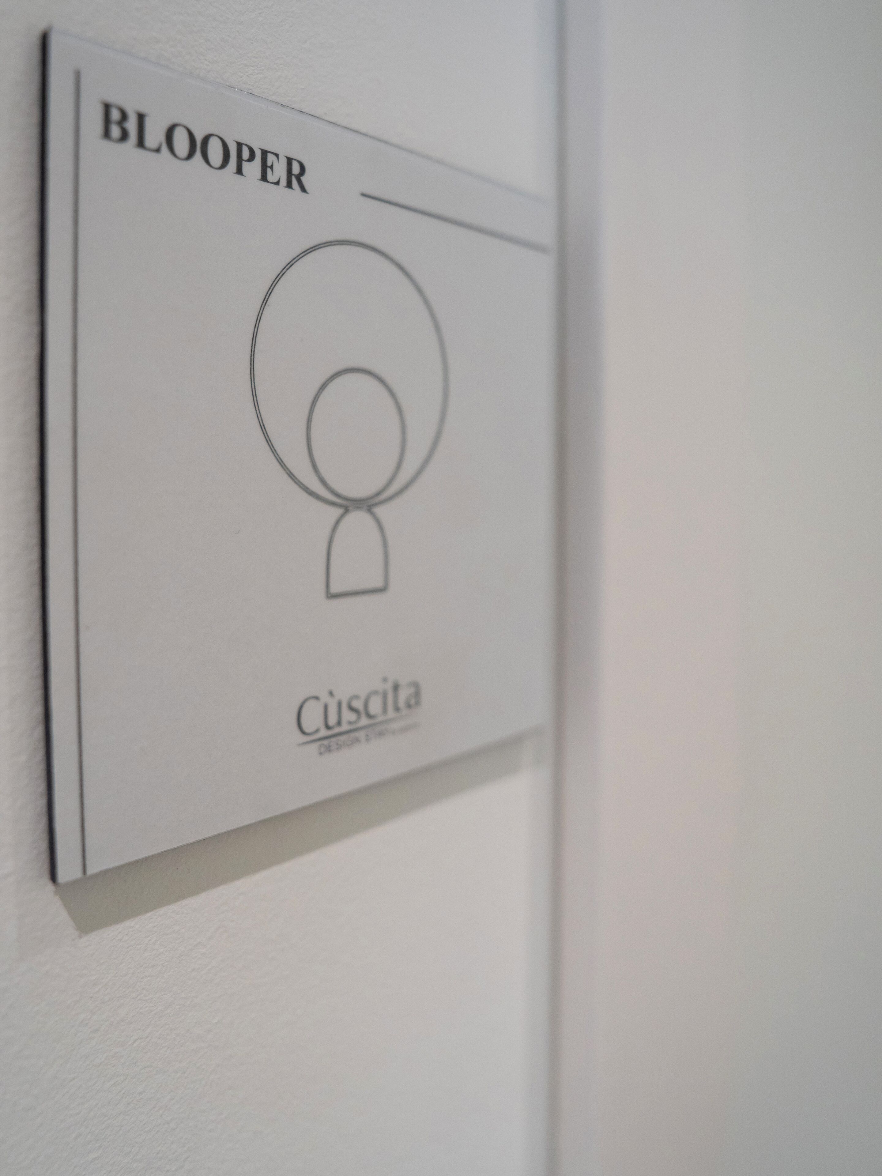 A wall-mounted sign with the text 'BLOOPER' and 'Cúscita' indicating a design or branding element.