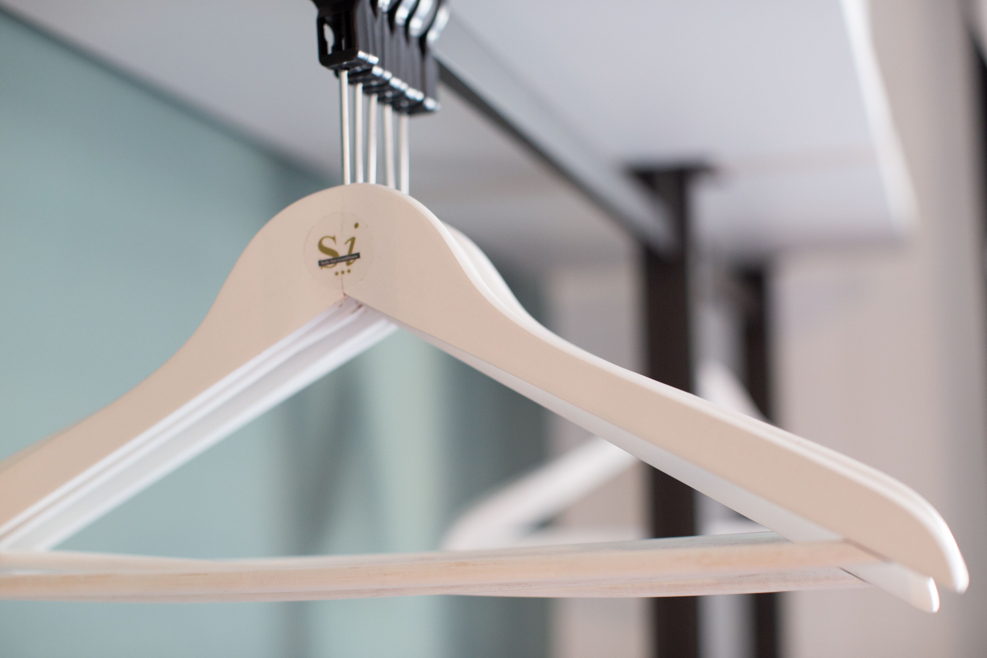 A white hanger with a logo, suspended from a black clip.