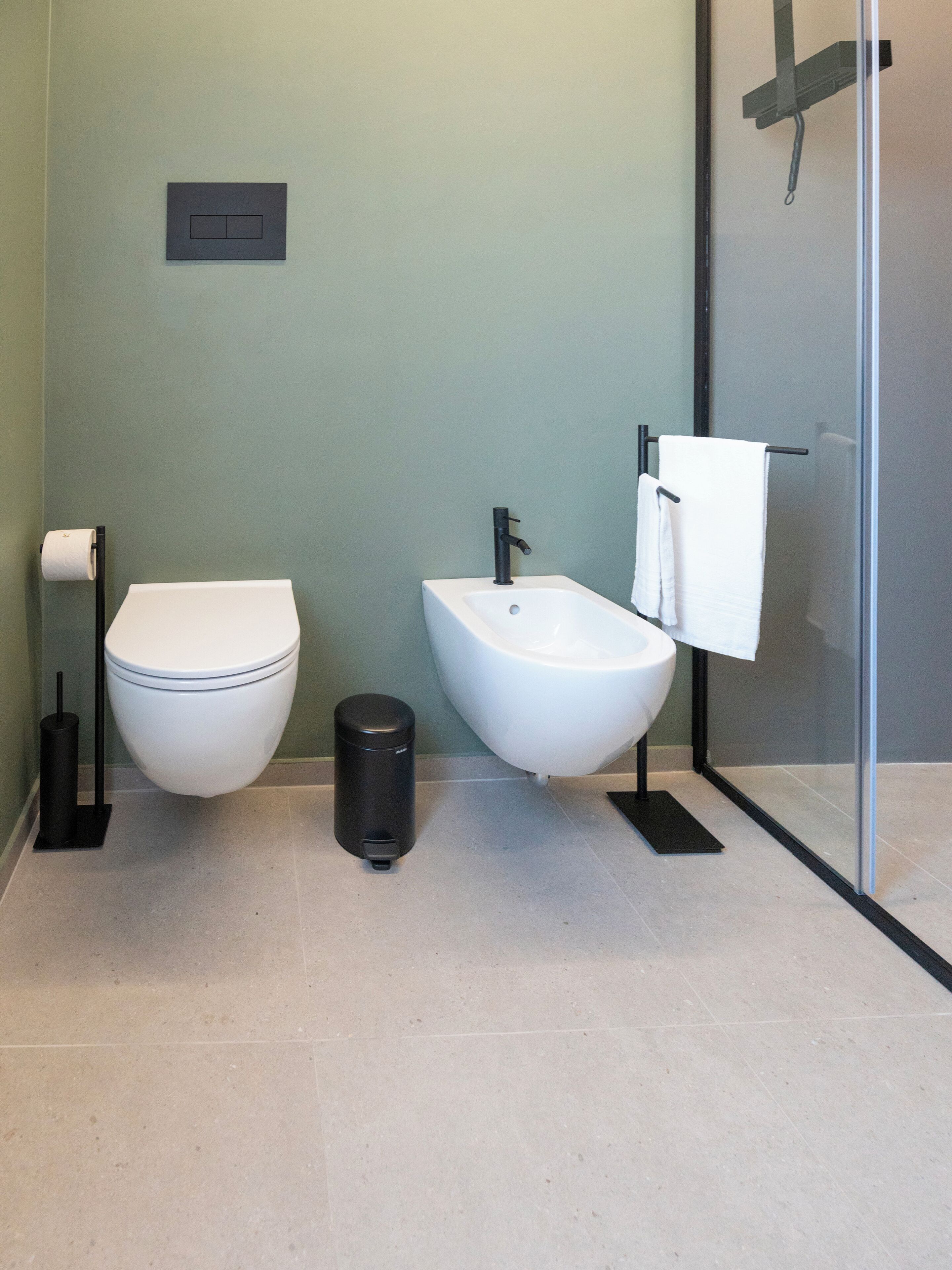 Un baño moderno con inodoro, bidé y cabina de ducha de vidrio.