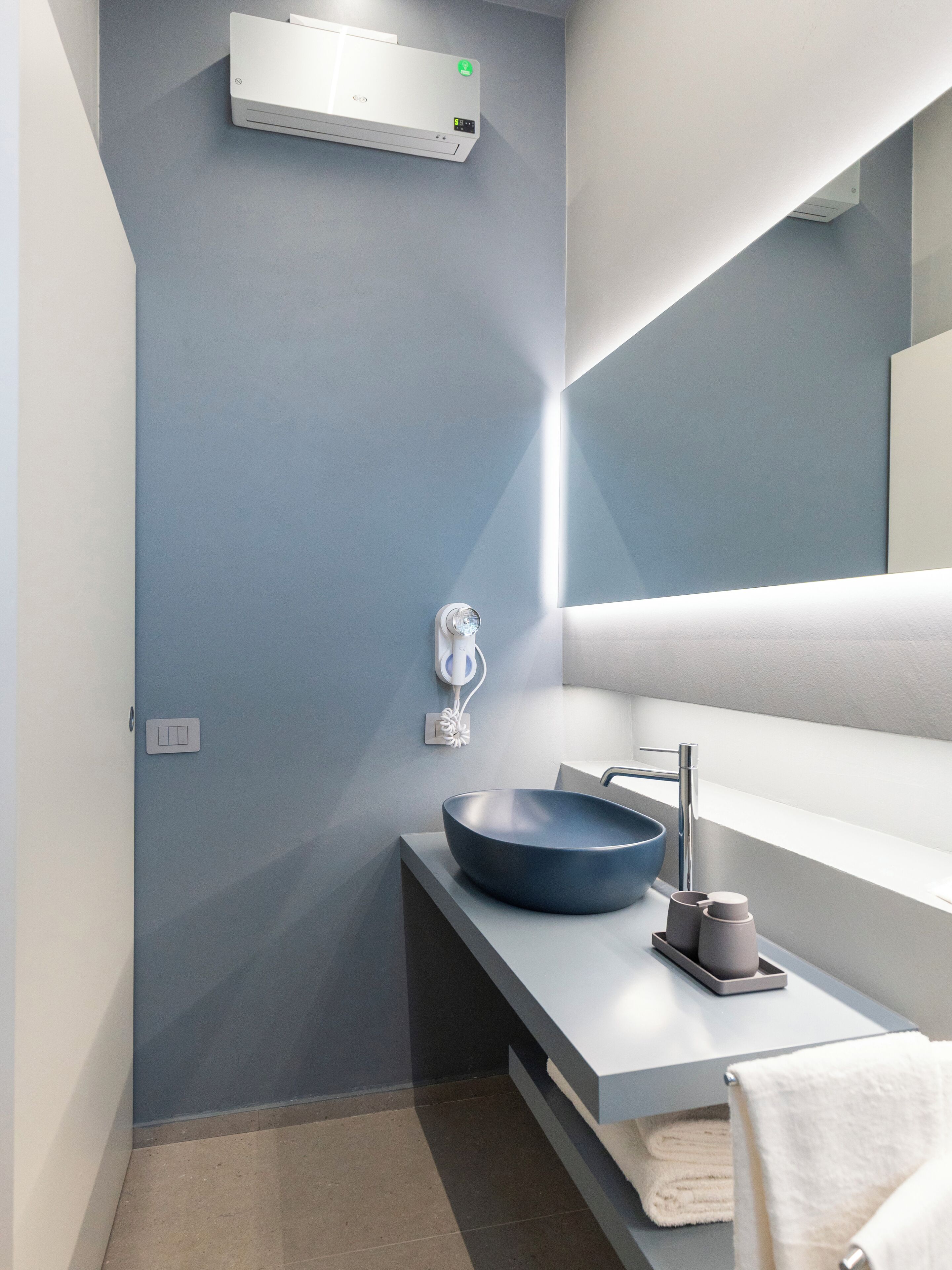 Un bagno moderno con lavandino incassato, portasciuga asciugamani e condizionatore d'aria a parete.