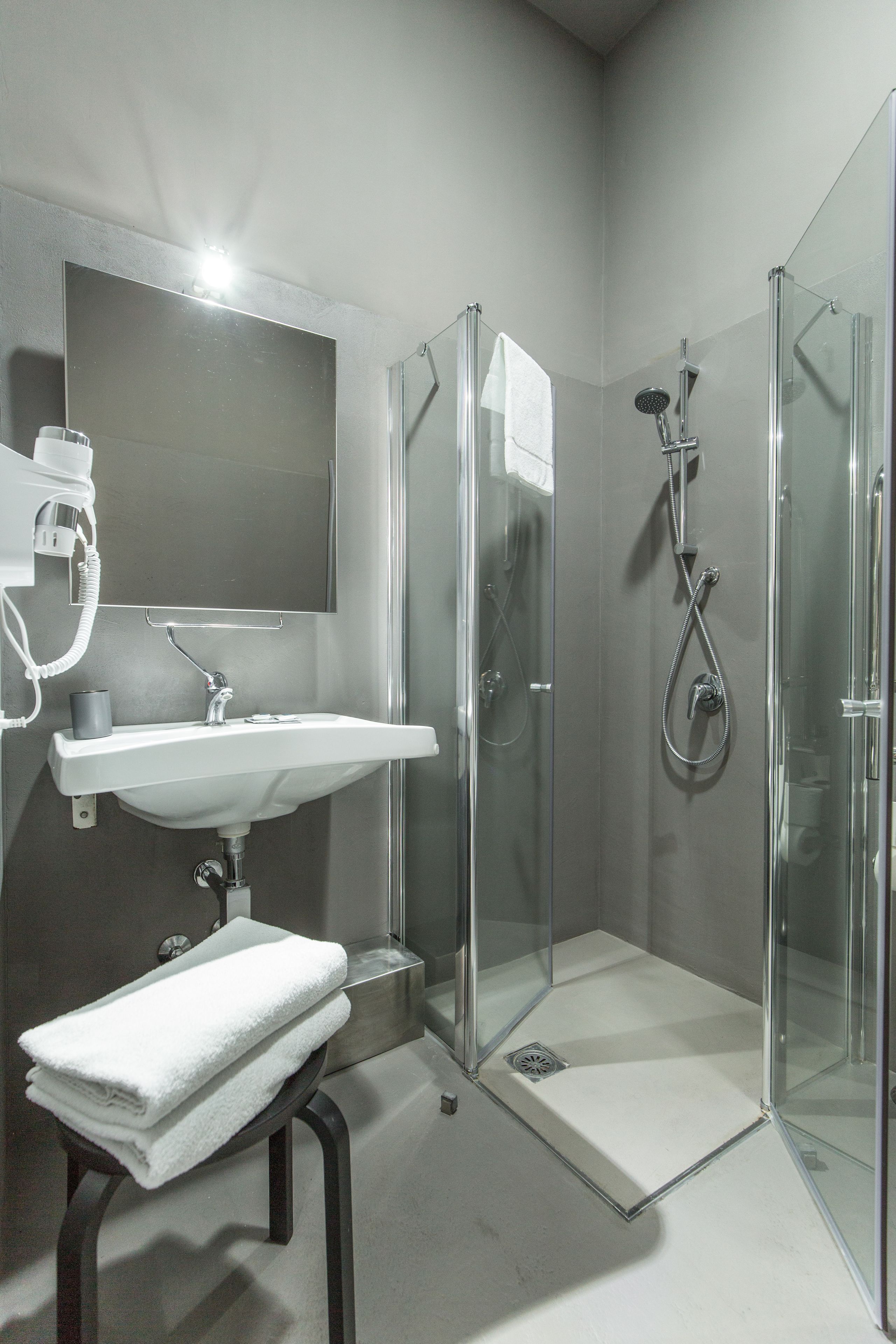 Un bagno moderno con doccia vetrata, un lavandino bianco e uno specchio sopra il lavandino.