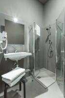 Un bagno moderno con doccia vetrata, un lavandino bianco e uno specchio sopra il lavandino.