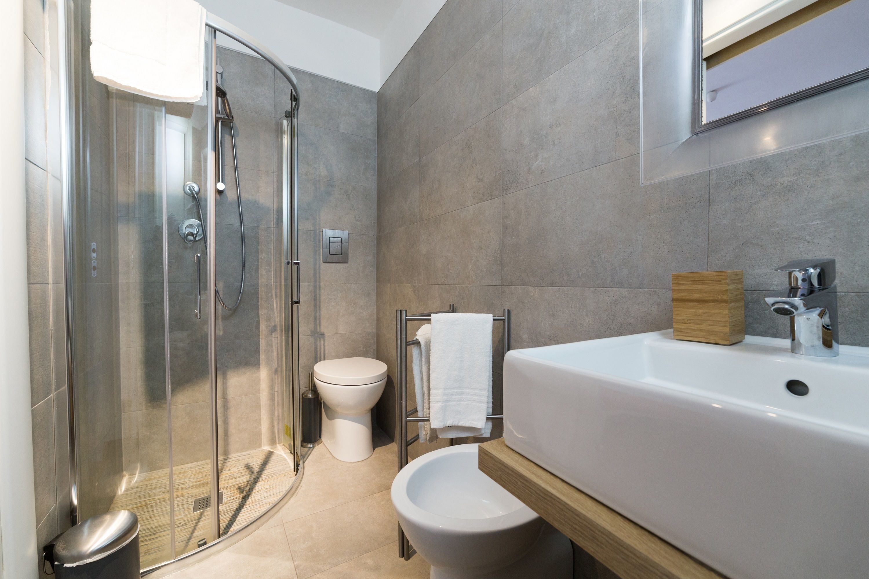 Un bagno moderno con doccia vetro, toilette, bidet e una grande vasca da bagno.