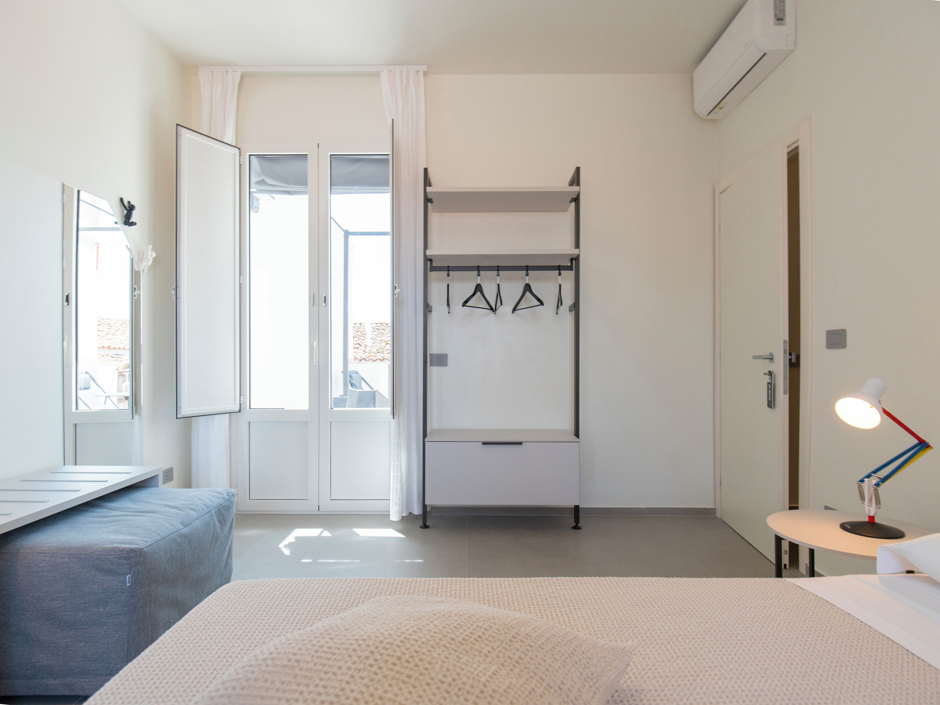 Ein Schlafzimmer mit Etagenbett, Schreibtisch, Stuhl, Lampe und einem fensterbepflanzten Fenster.