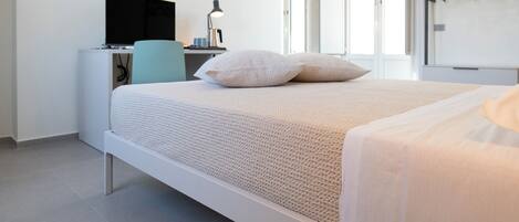 A modern bedroom with a bed, a desk, a chair, a TV, and a wardrobe.