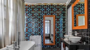 Un baño moderno con pared de mosaicos, un espejo grande, una bañera y dos lavamanos.