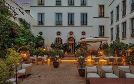 A courtyard with outdoor seating, potted plants, and a building with multiple windows and balconies.