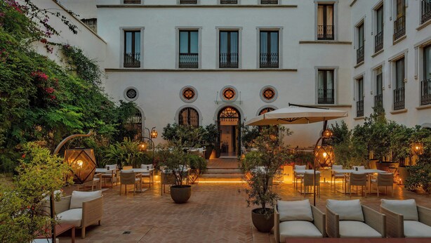 A courtyard with outdoor seating, potted plants, and a building with multiple windows and balconies. - CoolRooms Palacio Villapanés 5 GL (Seville)