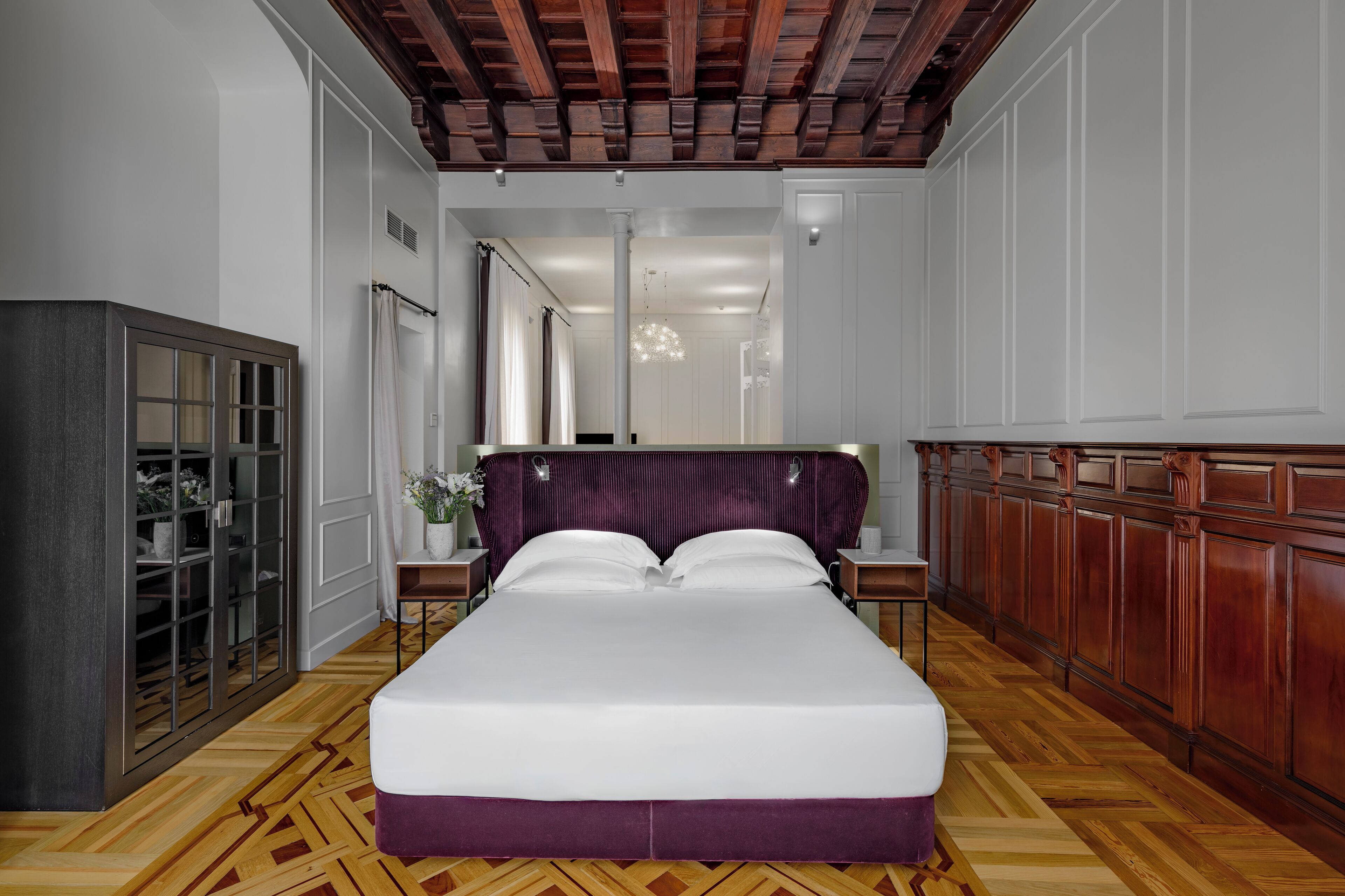 A hotel room with a large bed, a wardrobe, a desk, and a mirror.