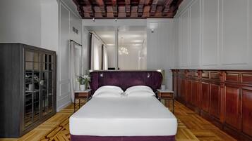 A hotel room with a large bed, a wardrobe, a desk, and a mirror.