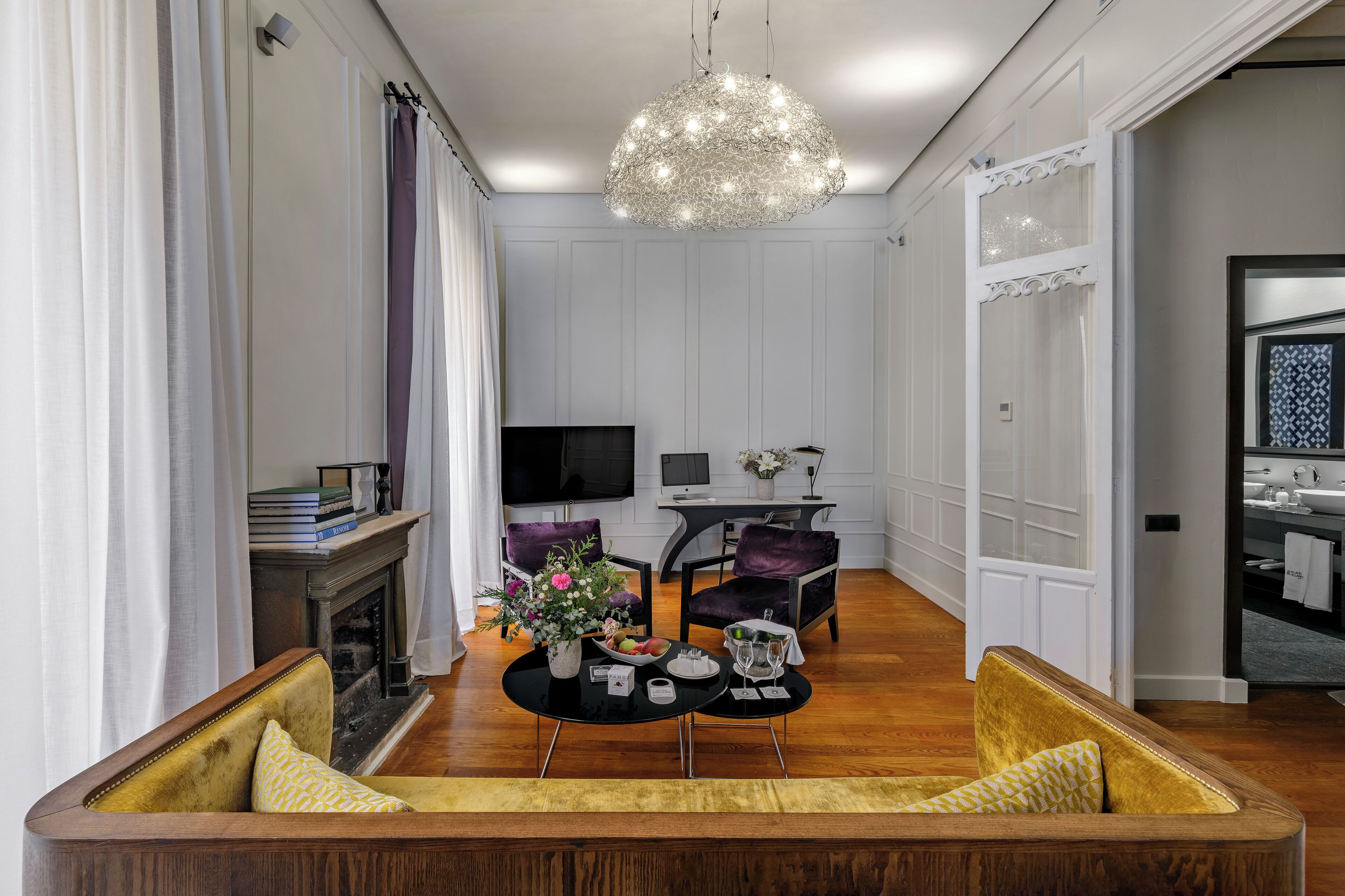 Un salon moderne avec une cheminée, une table à manger agrémentée d’un vase de fleurs, un canapé et un téléviseur.