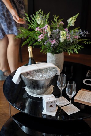 A table with a bottle of champagne, ice, two glasses, a bouquet of flowers, and a box labeled "PANG." - CoolRooms Palacio Villapanés 5 GL (Seville)