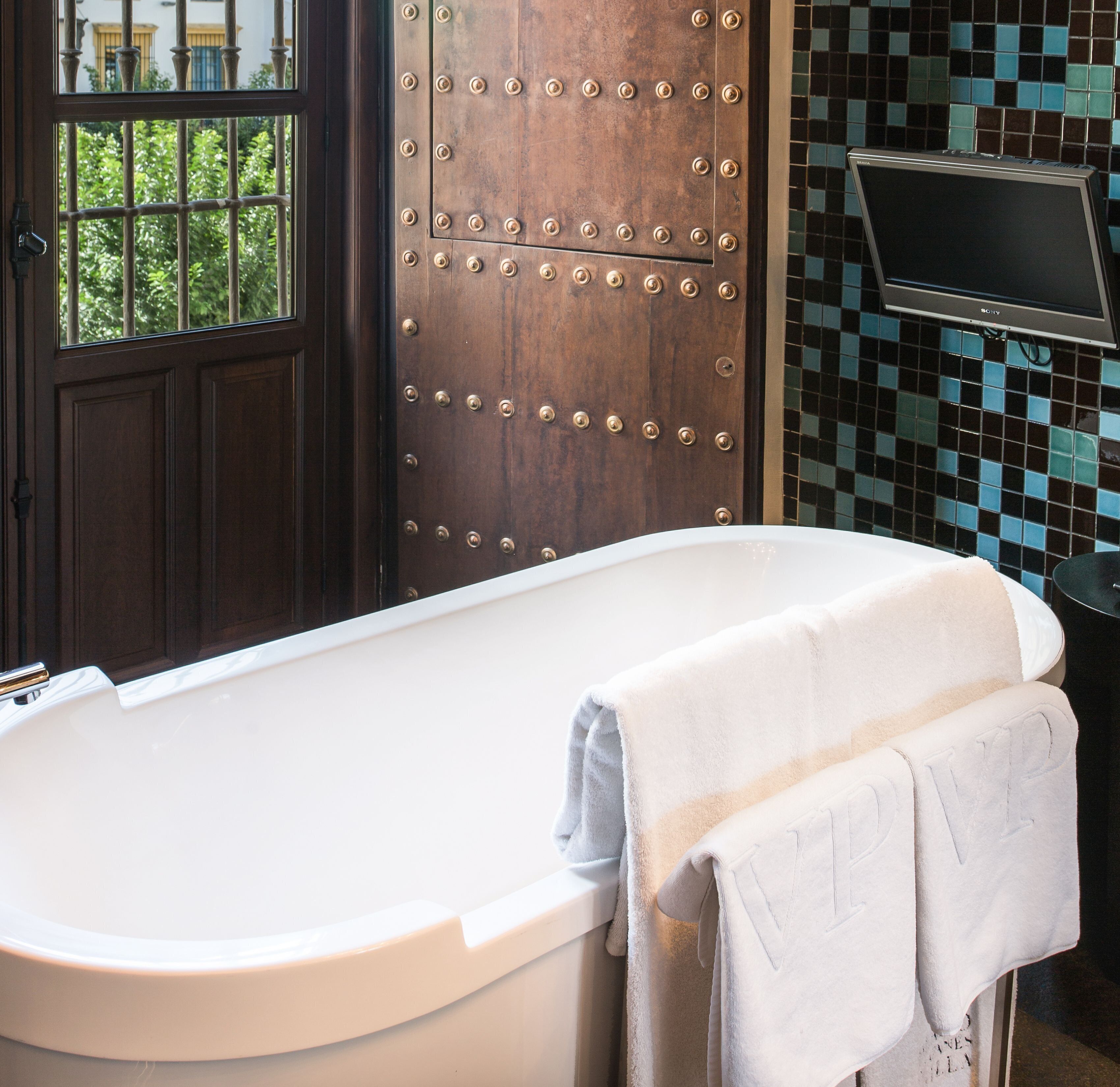 Un baño con una bañera, una puerta de madera con remaches metálicos y una pared de azulejos.