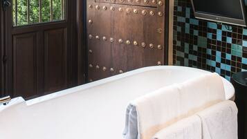 Un baño con una bañera, una puerta de madera con remaches metálicos y una pared de azulejos.
