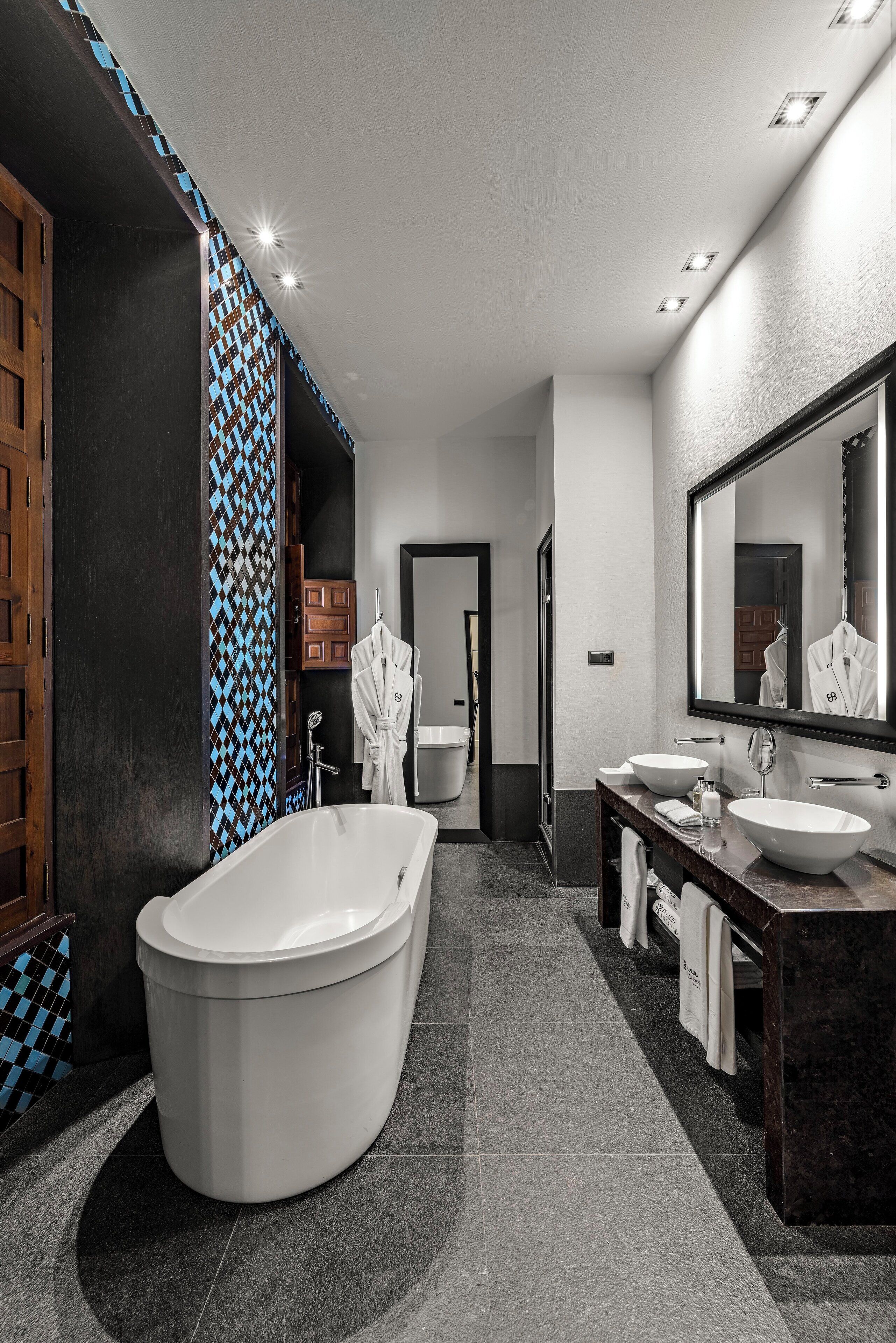 Une salle de bain moderne avec une baignoire sur pieds, un grand miroir et un meuble-lavabo doté de deux vasques.