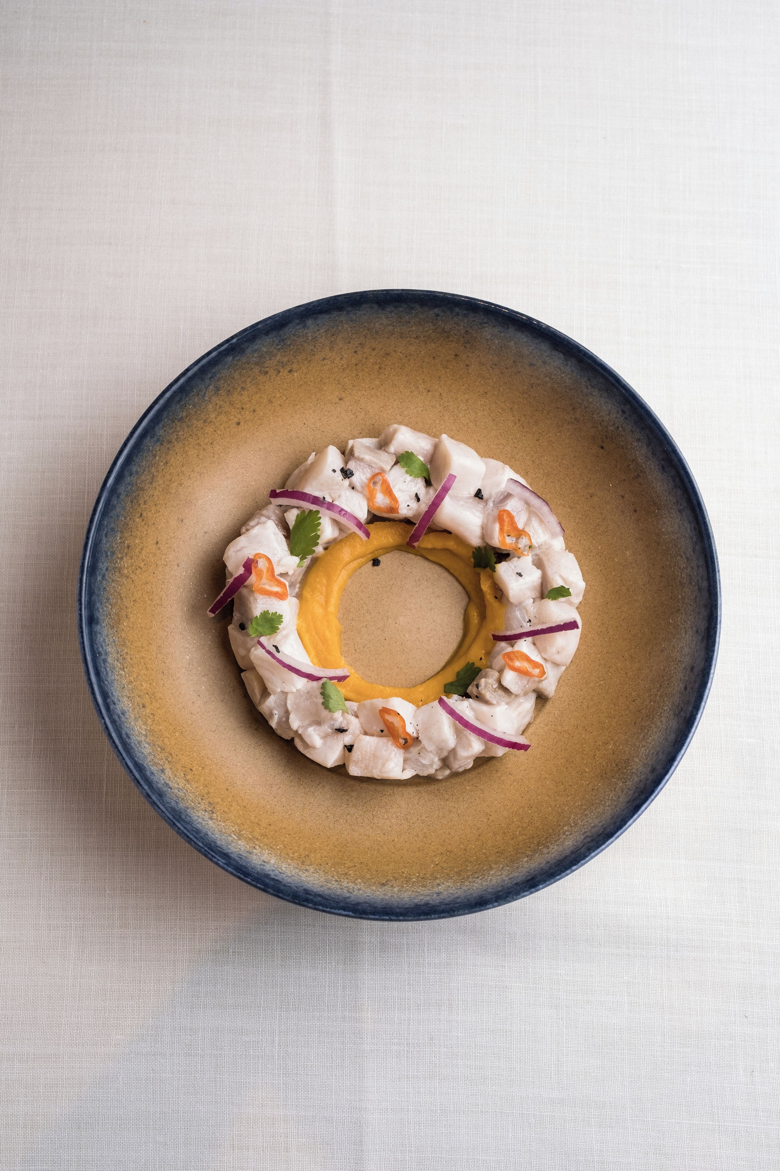 Une assiette ronde avec un trou au centre, ornée d’une présentation décorative de différents aliments.