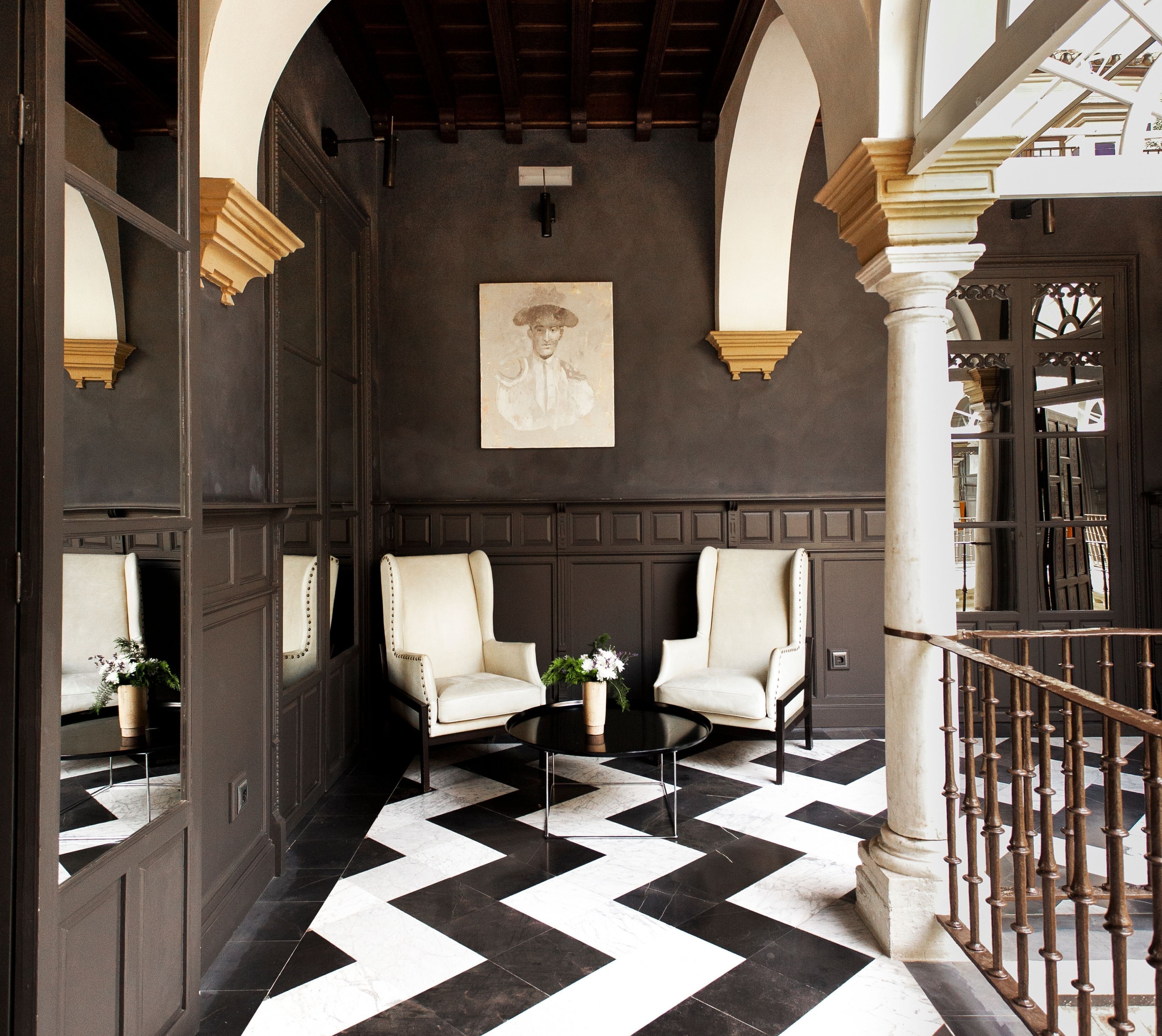A lobby with two white armchairs, a small round table, and a black and white checkered floor.