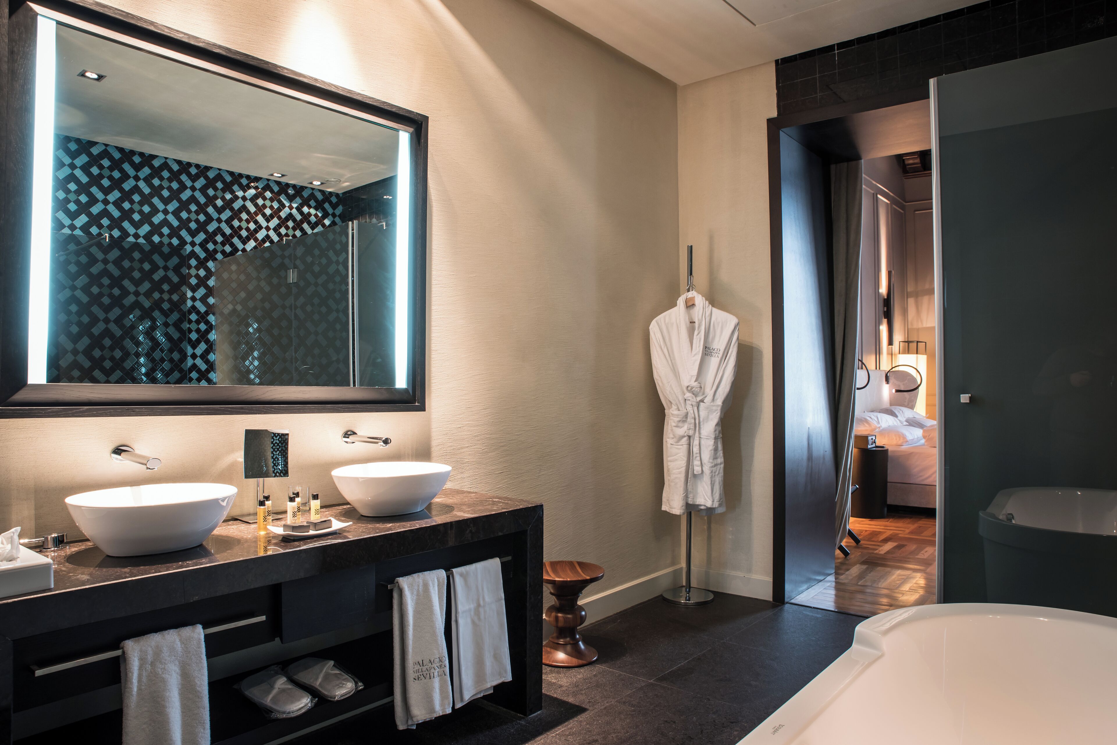 A modern bathroom with two large white sinks, a large mirror, and a bathtub.
