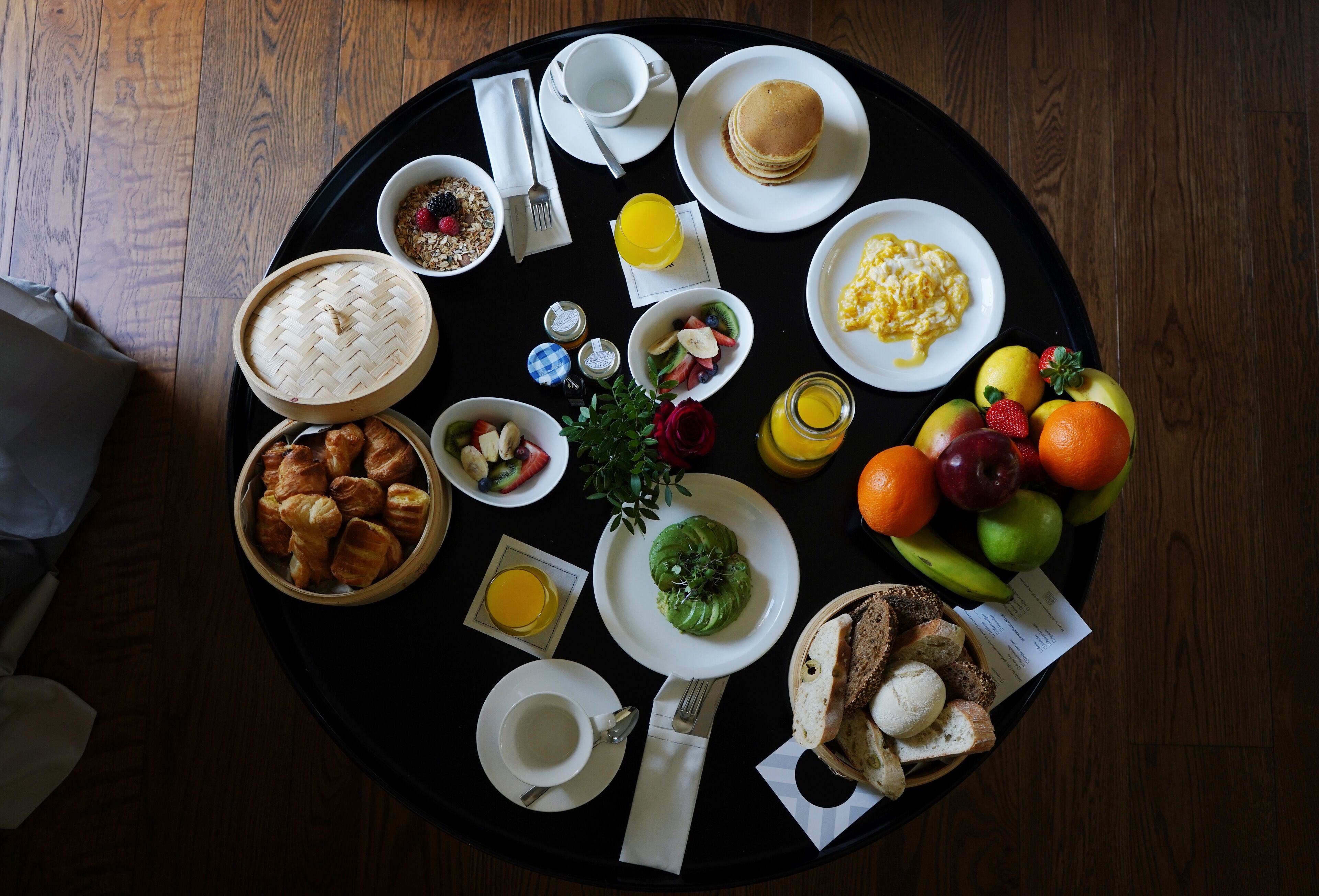 A breakfast tray with various food items including pancakes, eggs, fruits, and pastries.