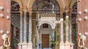 A grand entrance with a marble staircase, ornate metal gates, and a patterned floor. - CoolRooms Palacio Villapanés 5 GL (Seville)