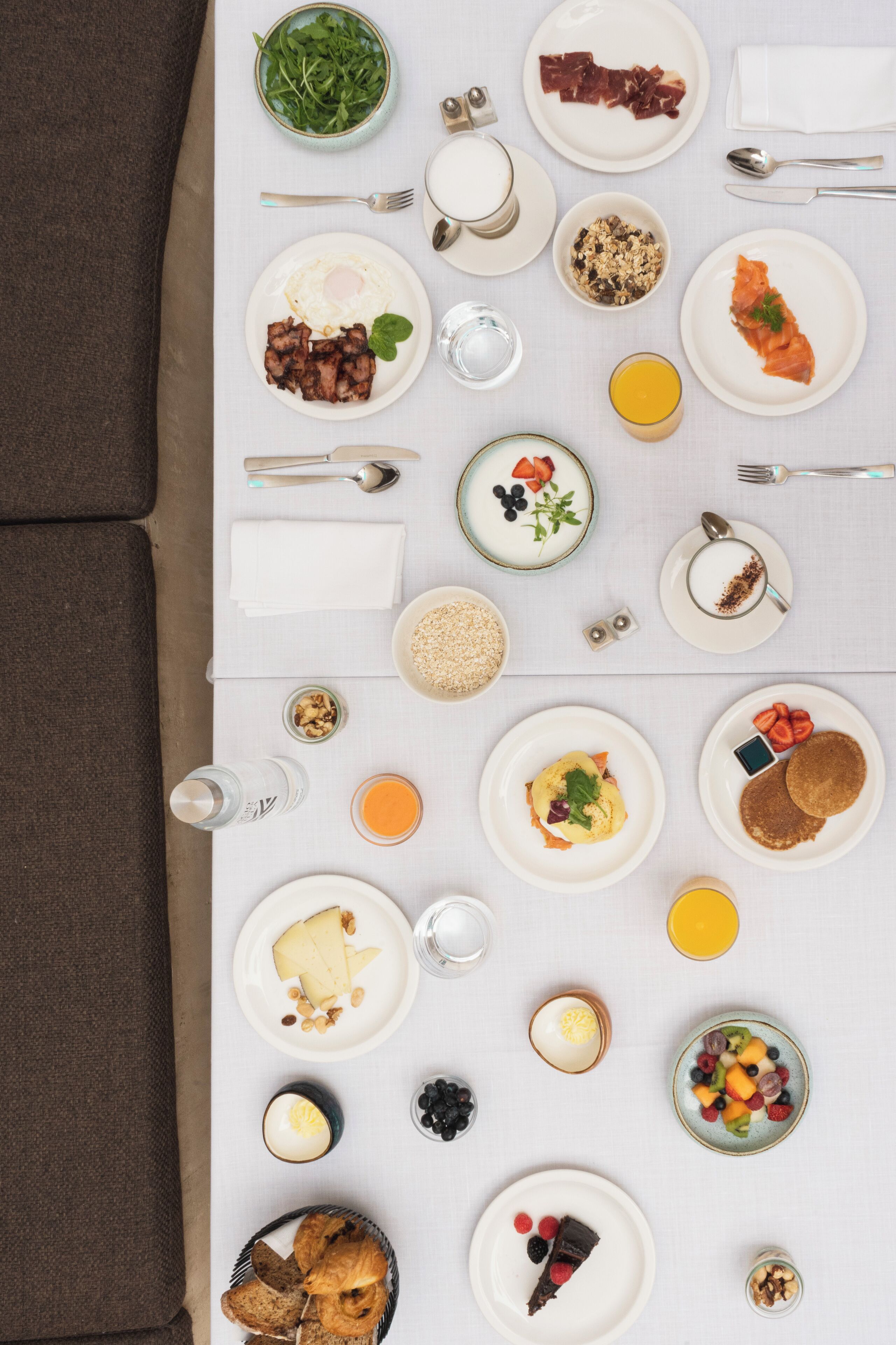 A breakfast spread on a table with various dishes, including eggs, bacon, and pastries.