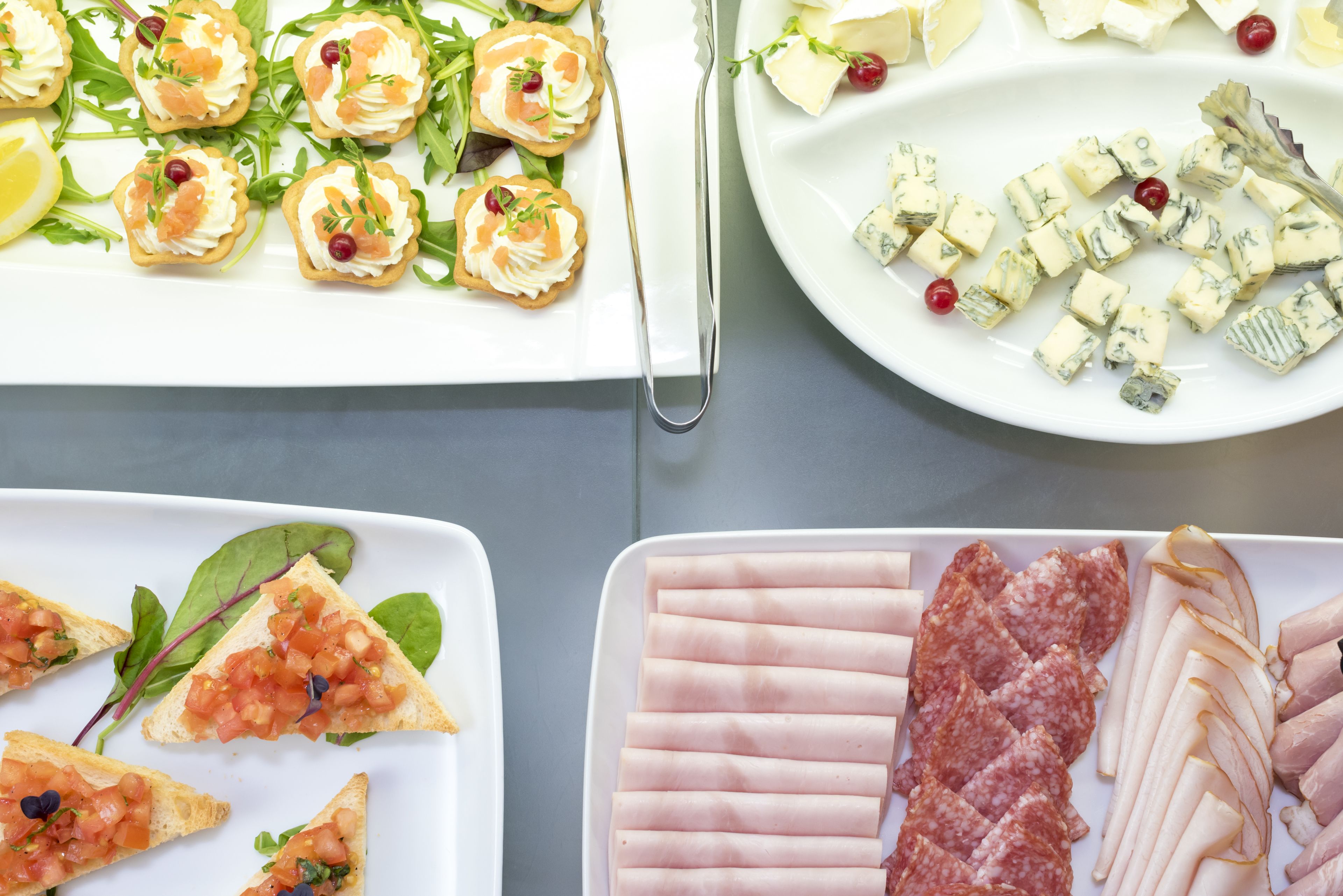 Diversos tipos de comida, incluyendo aperitivos, queso y carnes, dispuestas en platos.