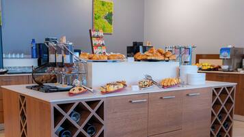 A breakfast buffet with various pastries, a coffee station, and a wine cooler.