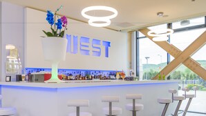 A modern bar area with a large sign reading "WEST," bar stools, and a variety of bottles on the counter. - West City Hotel (Floresti)
