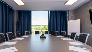 A conference room with a long table, blue curtains, and a view of the countryside. - West City Hotel (Floresti)