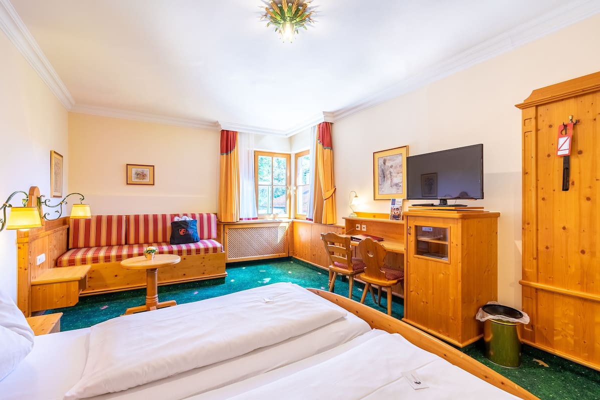 Ein Hotelzimmer mit Bett, Sofa, Schreibtisch und Fernseher.