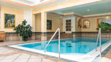 Ein Hallenbad mit gefliestem Boden, Metallleiter und Kunstwerken an den Wänden.