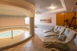 A spa area with a hot tub, lounge chairs, and a wooden wall with a painting. - Hotel-Restaurant Zum Schwarzen Bären (Emmersdorf an der Donau)