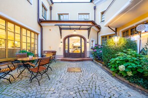 A courtyard with cobblestone flooring, a wooden table with chairs, and a potted plant. - Hotel-Restaurant Zum Schwarzen Bären (Emmersdorf an der Donau)